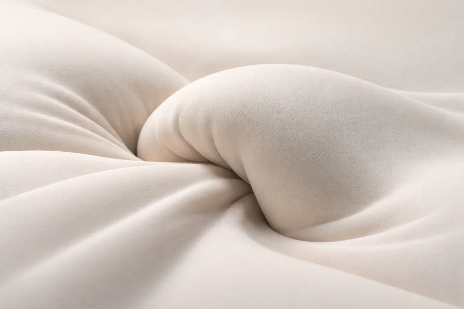 Oreiller ergonomique couleur sable formant un creux central doux sur une surface textile, évoquant le soutien cervical et le confort nocturne.